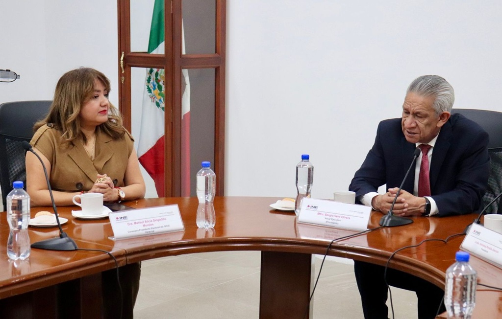 una mujer y un hombre sentados frente a una mesa con micrófonos
