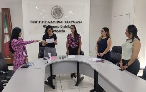 cinco mujeres de pie, una de ellas con el brazo extendido al frente