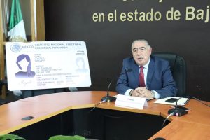 Un hombre sentado a un lado de la imagen de la Credencial para Votar