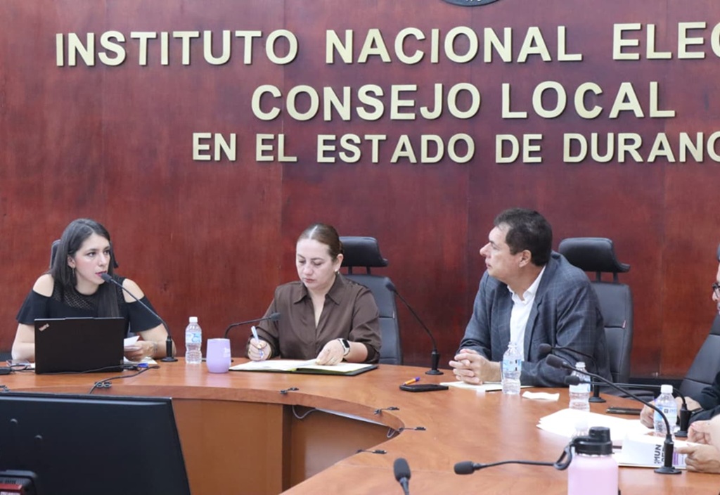 dos mujeres y un hombre frente a una mesa con micrófono
