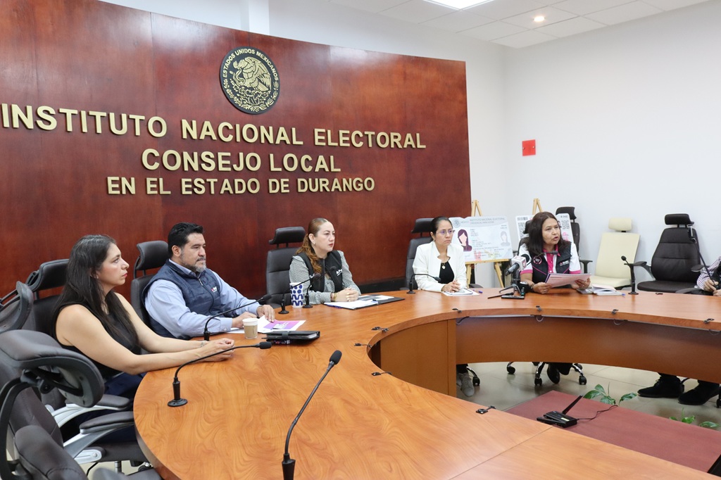 varias personas sentadas atrás de una mesa ovalada con micrófonos