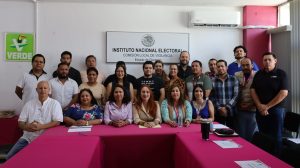 varias personas de pie y sentadas en un salón para la fotografía oficial