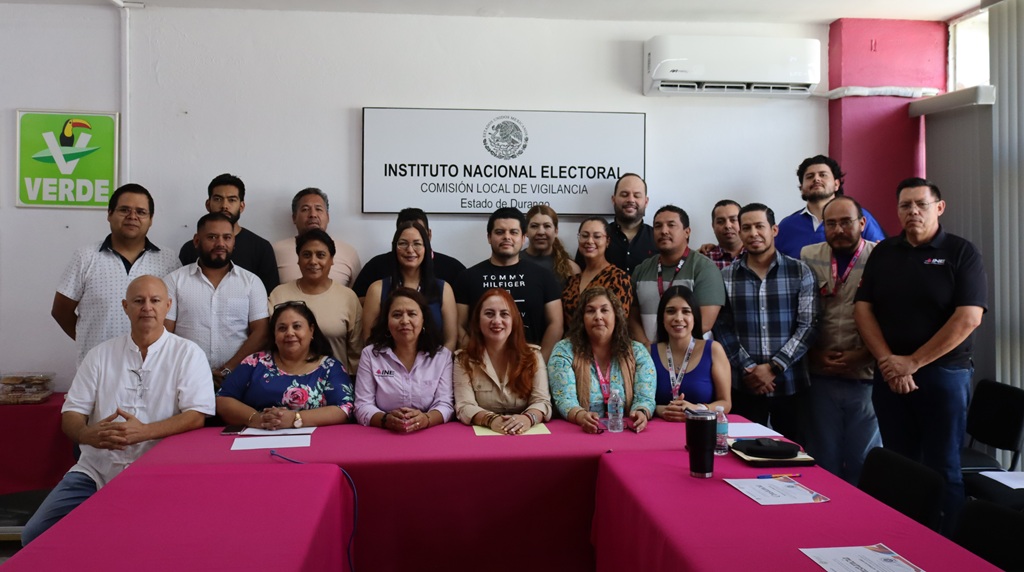 varias personas de pie y sentadas en un salón para la fotografía oficial
