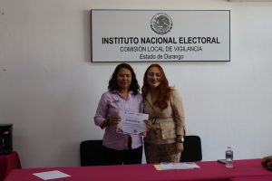 dos mujeres de pie, una de ellas sostiene un diploma