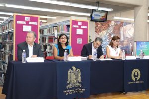 dos mujeres y dos hombres sentados frente a un a mesa con mantel color azul