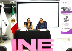 una mujer y un hombre están sentados y enfrente tres letras color rosa