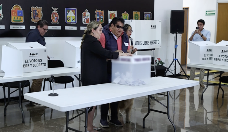 Mujer auxiliando a hombre invidente para votar