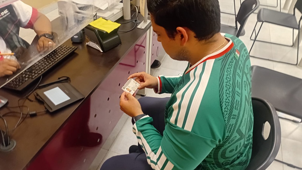 una persona joven viendo su credencial para votar