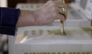 Imagen de mano metiendo voto a una urna