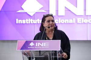 Guadalupe Taddei Zavala, Consejera Presidenta parada en el pódium participando en la conferencia.