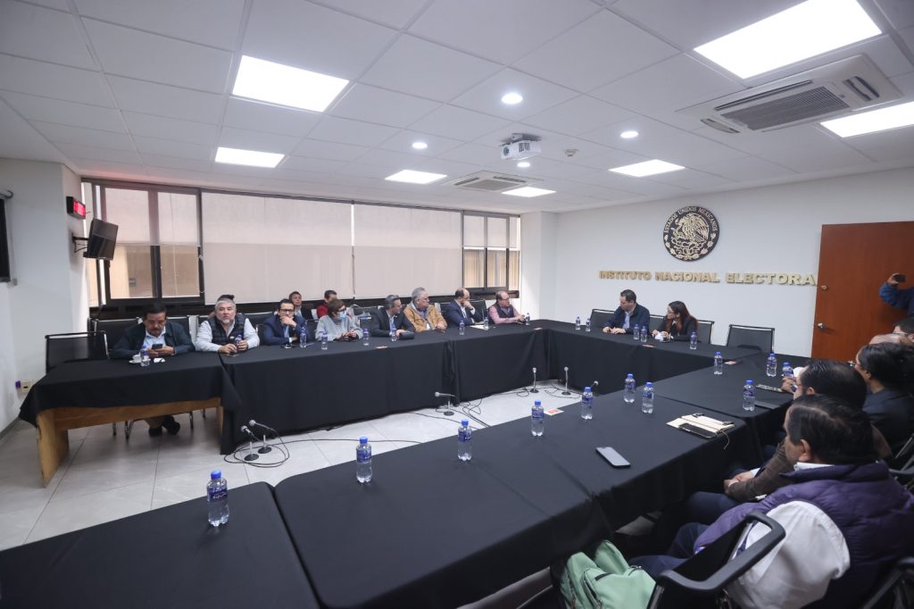 Representantes de los partidos Somos México y PAZ con funcionarios del INE sentados en el salón de usos múltiples.