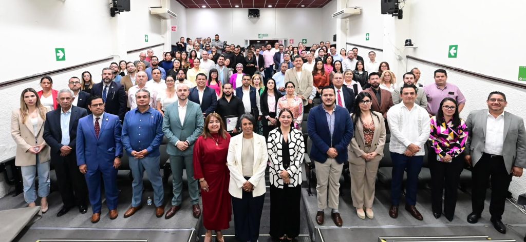 Personas participantes y público asistente paradas en el salón posando para la foto.