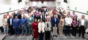 Personas participantes y público asistente paradas en el salón posando para la foto.