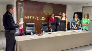 Una mujer con el brazo derecho extendido al frente, varias personas atrás