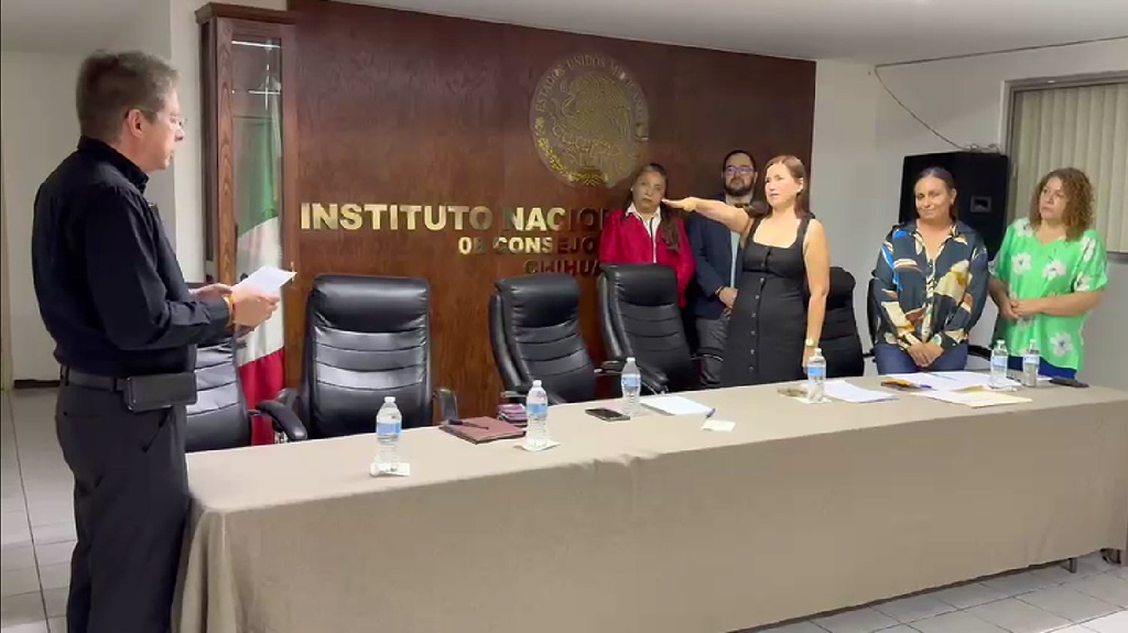 Una mujer con el brazo derecho extendido al frente, varias personas atrás