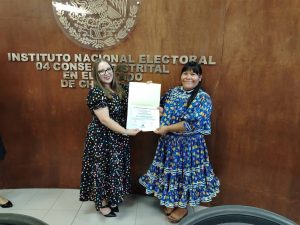 Dos mujeres de pie sostienen un documento