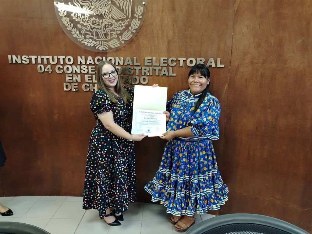 Dos mujeres de pie sostienen un documento
