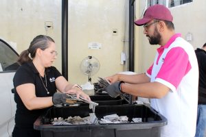 dos personas de pie frente a una caja con credenciales para votar sin validez