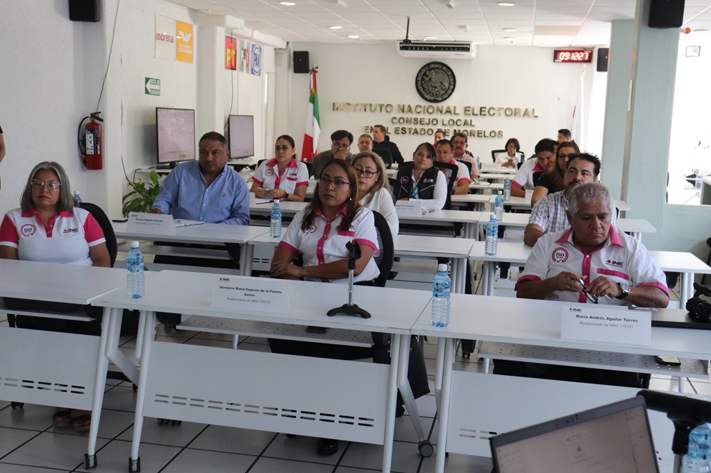 personas sentadas frente a mesas blancas con micrófonos