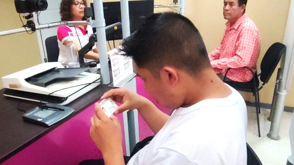 Un joven revisando los datos de su credencial para votar con fotografías