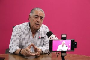 hombre sentado frente a un micrófono y un celular
