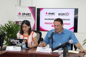 una mujer y un hombre sentados frente a micrófonos
