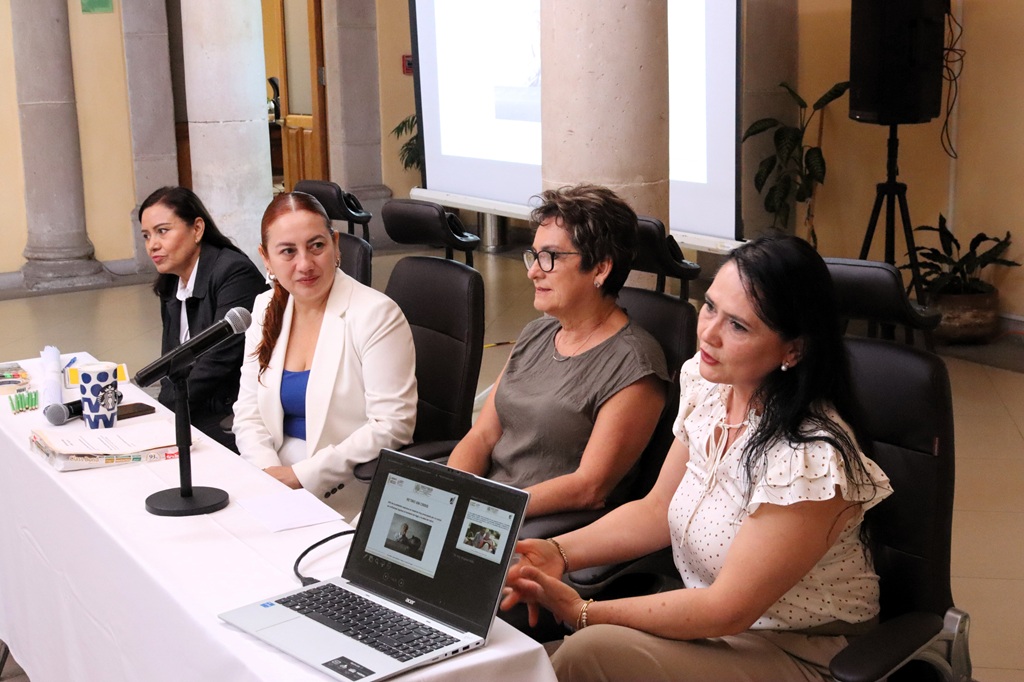 cuatro mujeres sentadas frente a una mesa con micrófonos