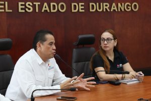 una mujer cabello rojo y un hombre sentados platicando