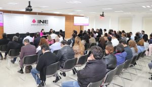 muchas personas sentadas frente a una pantalla