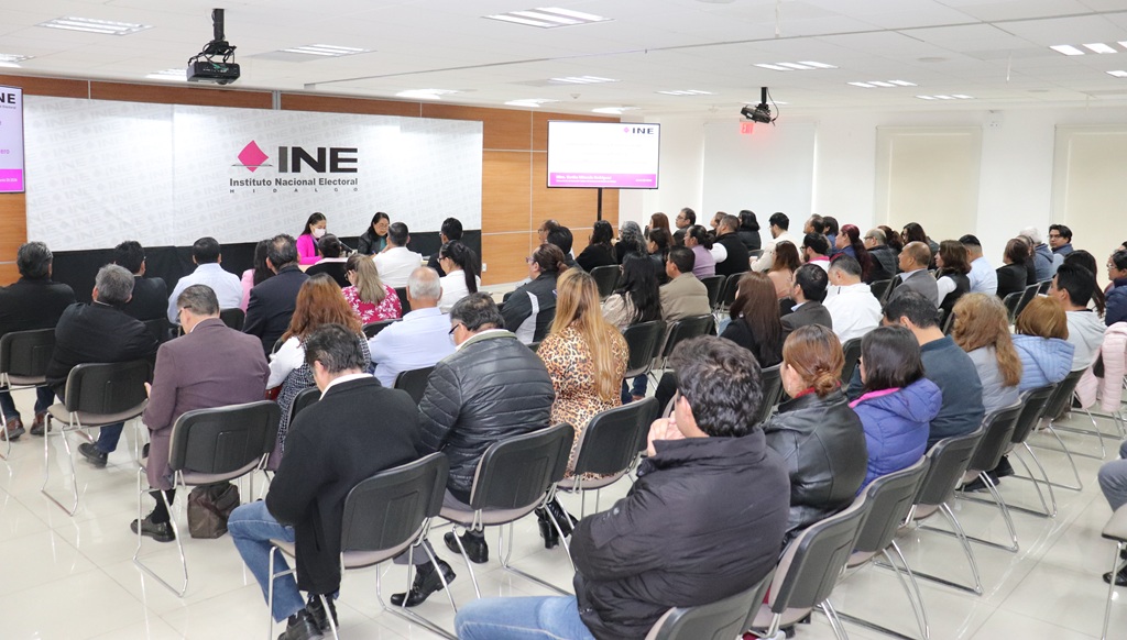 muchas personas sentadas frente a una pantalla