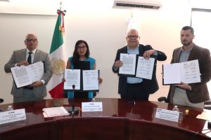 una mujer y tres hombres, cada persona sostiene un documento