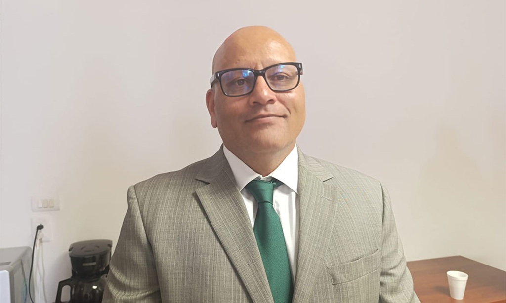 Hombre de lentes, calvo con saco y corbata verde y camisa blanca