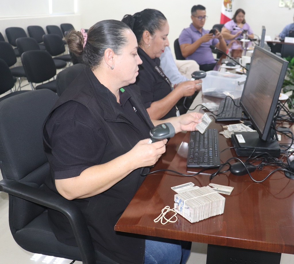 dos mujeres sentadas con una maquina lectora de códigos QR en la mano