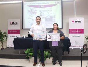 una mujer y un hombre de pie sosteniendo la imagen de la credencial para votar tamaño cartulina