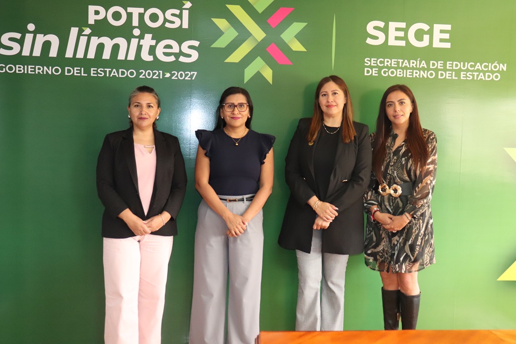 cuatro mujeres de pie frente a una pared color verde
