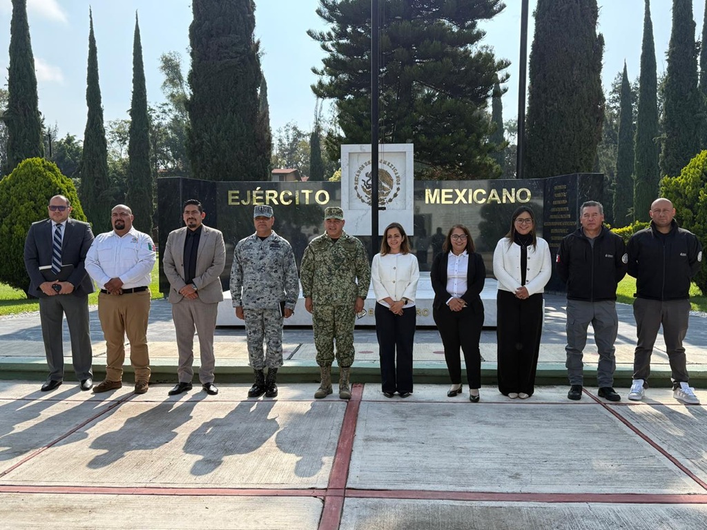 varias personas entre ellos militares de pie frente a un letrero del Ejercito Mexicano