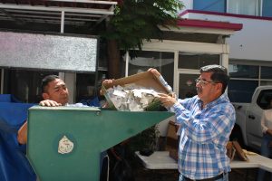 dos personas de pie a un lado de una trituradora color verde
