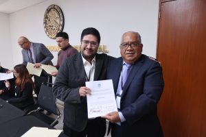 Dos personas sosteniendo un certificado en una sala de juntas