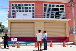 tres personas viendo un inmueble color rosa