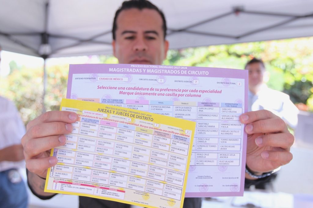Hombre presentando modelos de boletas de votación para jueces y magistrados