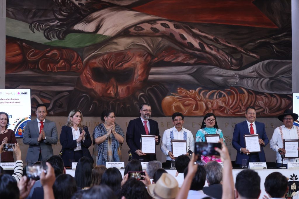 Personas participantes paradas en el estrado mostrando el documento.