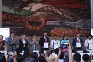 Personas participantes paradas en el estrado mostrando el documento.