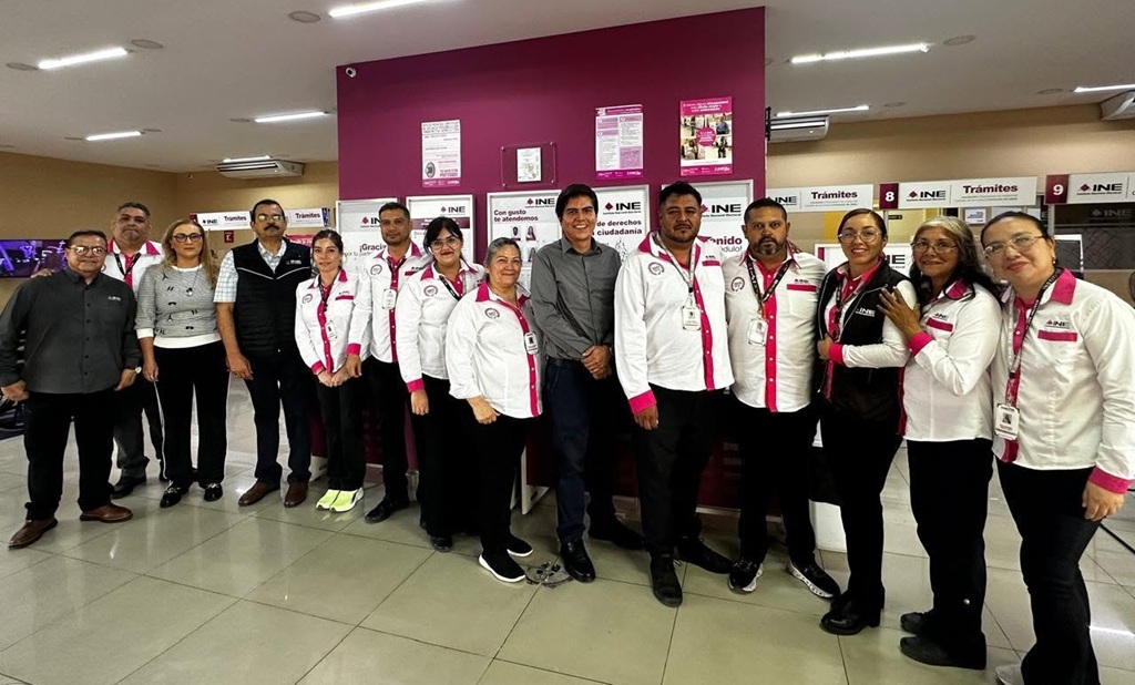 mas de diez personas con camisa blanca con rosa de pie para la foto oficial