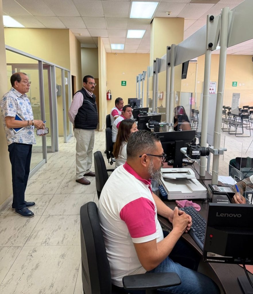 dos hombre de pie atrás de personas sentadas frente a computadoras