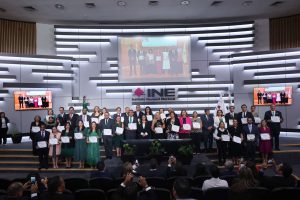 Personas participantes paradas con su reconocimiento en las manos.