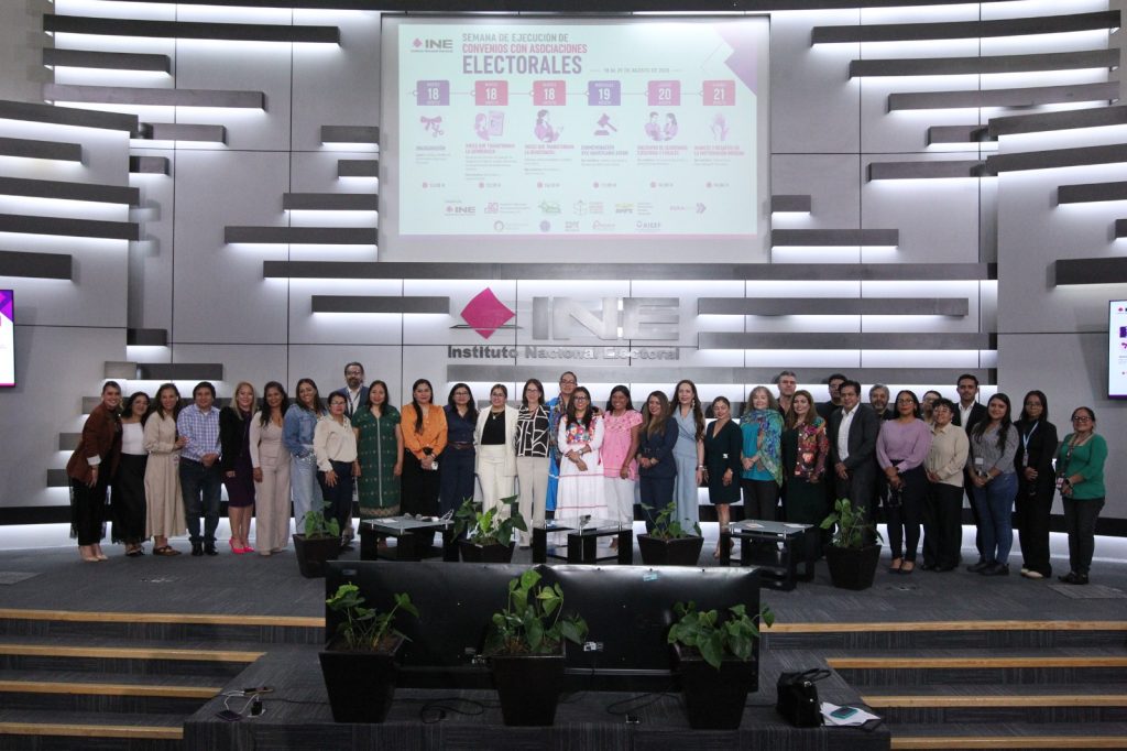 Personas participantes paradas en el estrado del auditorio posando para la foto.