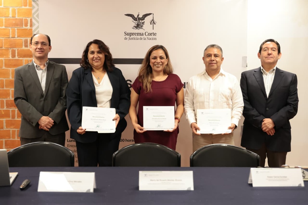 cinco personas de pie, tres sostienen un diploma