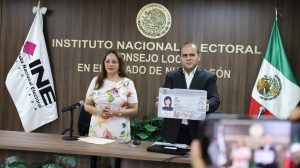dos personas de pie mostrando un modelo de credencia para votar