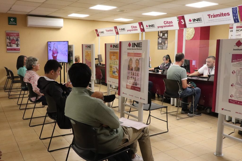 personas sentadas dentro de las instalaciones de un módulo del INE