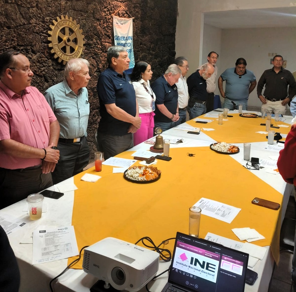 personas de pie alrededor de una mesa con mantel amarillo